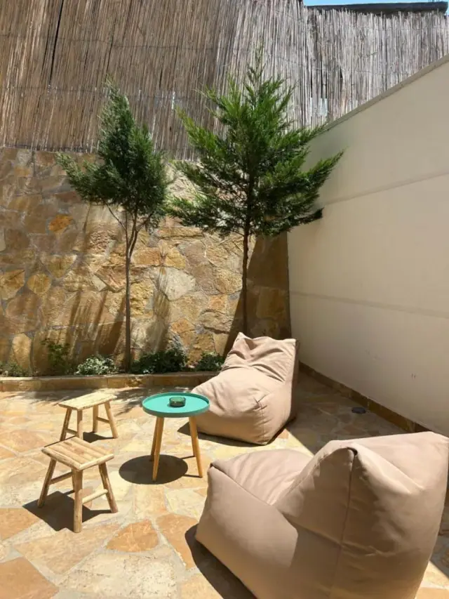A walled flagstone courtyard with beanbag seating and young cypresses