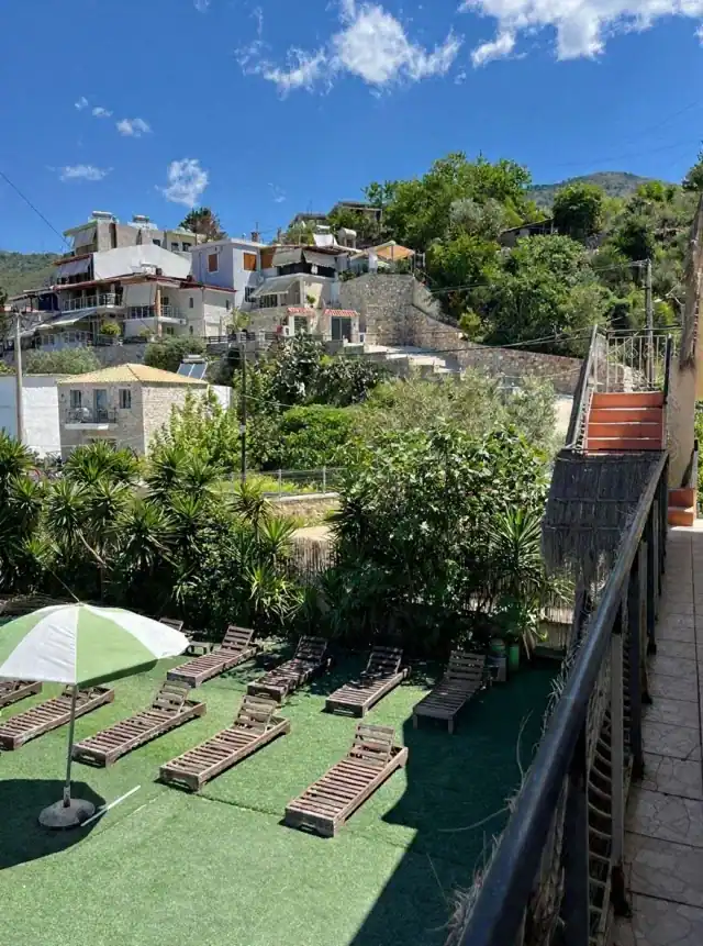 The sun terrace of loungers seen from the walkway, with stone houses and terraces climbing the hillside above