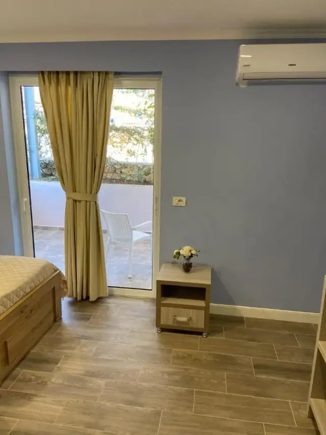 A room with yellow curtains drawn back from a glazed door onto a patio with a white chair