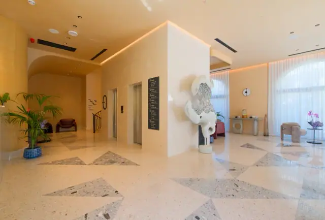 The lobby, pale terrazzo with grey triangles set into it under an arched soffit