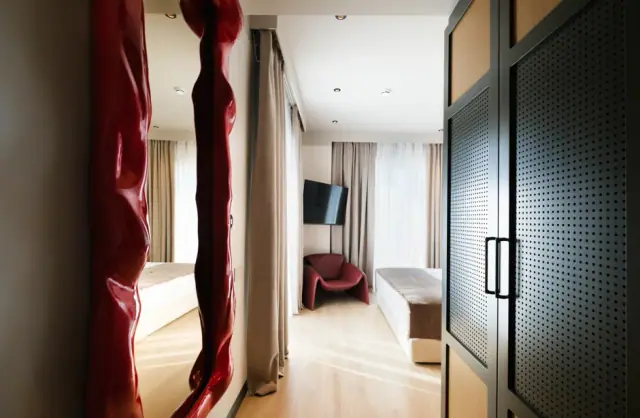 Junior Suite with the sculpted red mirror and the perforated dark green wardrobe doors