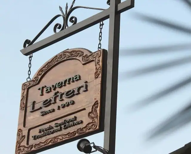 Close view of the carved sign reading Taverna Lefteri, Since 1998, Fresh Seafood, Traditional Dishes