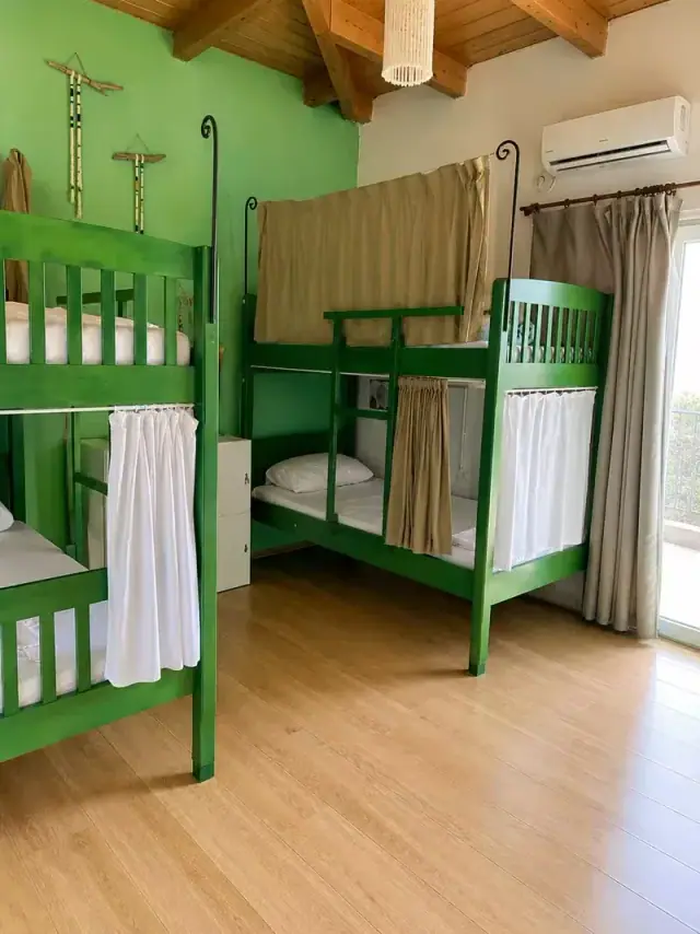 Green-painted bunk beds with curtains and a balcony door in a dorm at Trip'n'Hostel Seaside