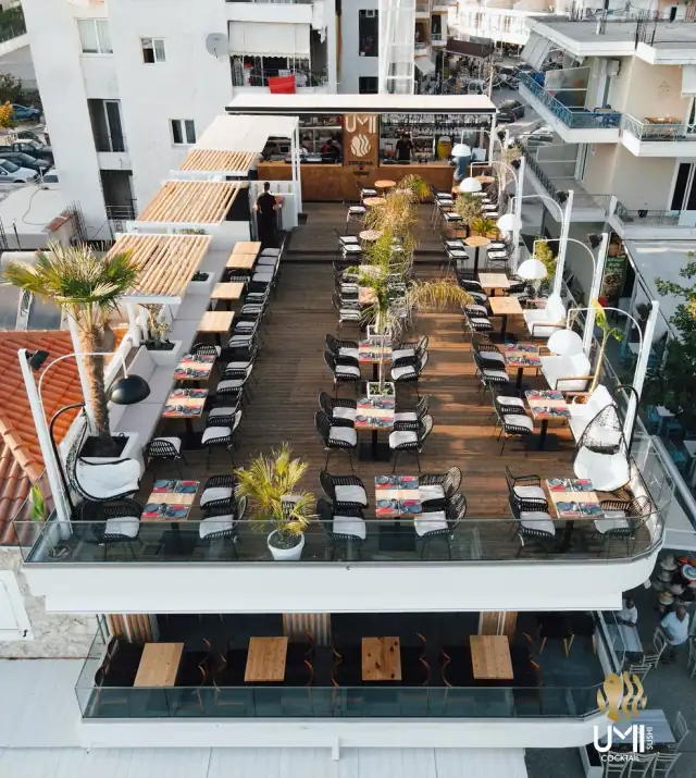 UMI's rooftop deck photographed from above, tables in three long runs along the timber decking, the open bar at the far end under its own wordmark