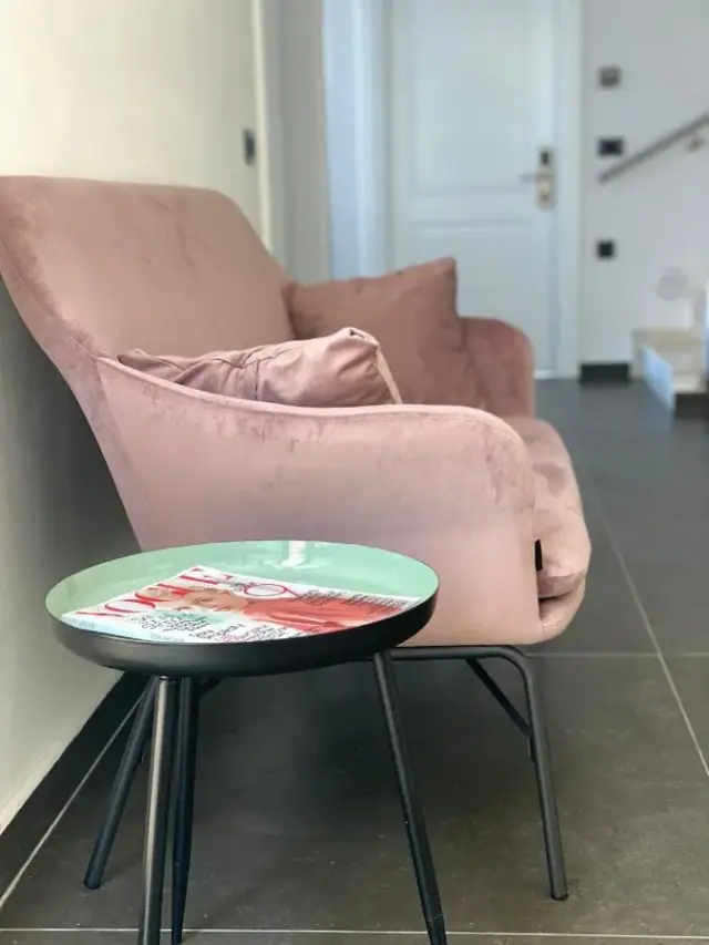 A dusty-pink velvet armchair and a small round black side table