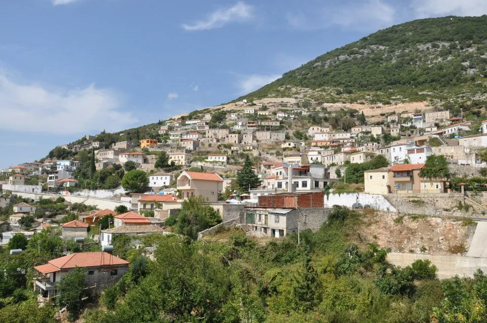 Vuno village, stone and plaster houses stacked up a green hillside