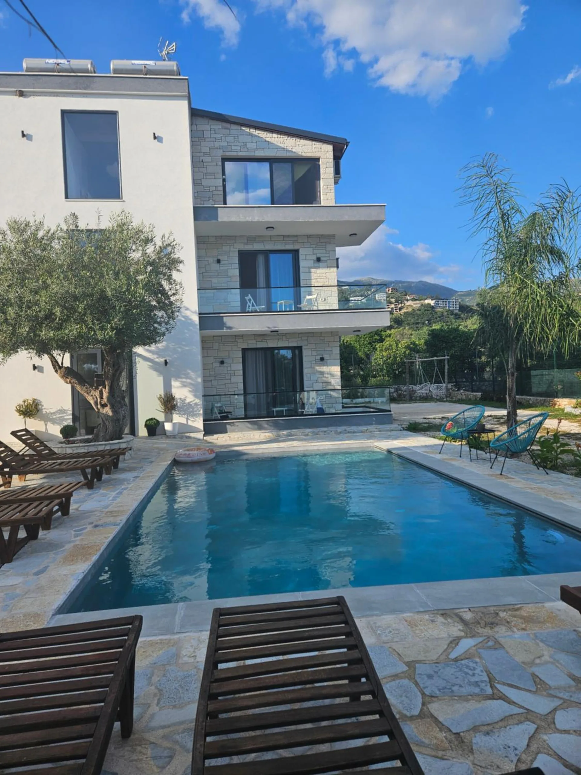 The length of the pool running up to the house, with loungers along both sides and glass balconies on every floor